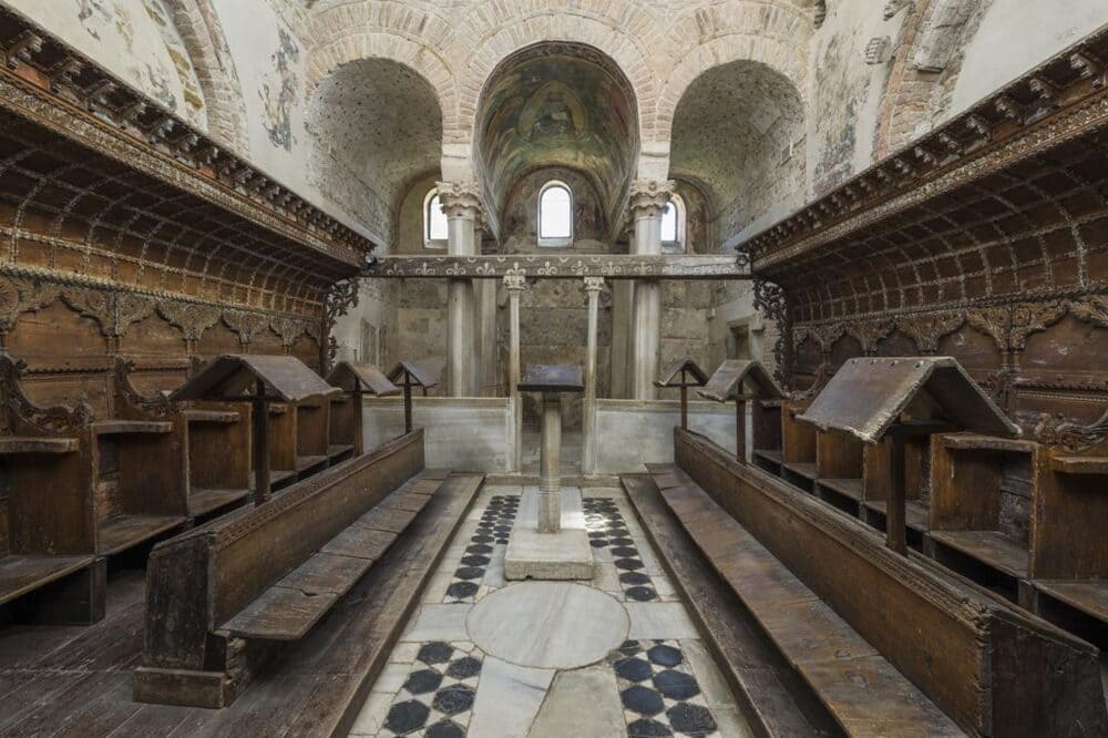 Interno del Tempietto Longobardo di Cividale: stalli lignei e archi antichi